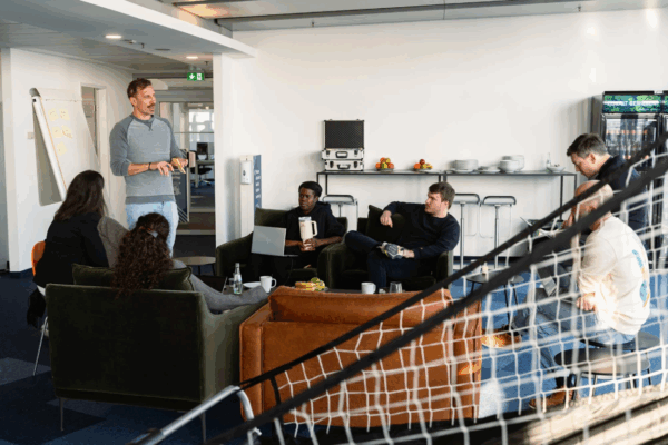 Team diskutiert in Open-Space-Büro, Vordergrund zeigt Tischkicker – Symbol für kreative, offene Arbeitskultur und soziale Interaktion im Team.