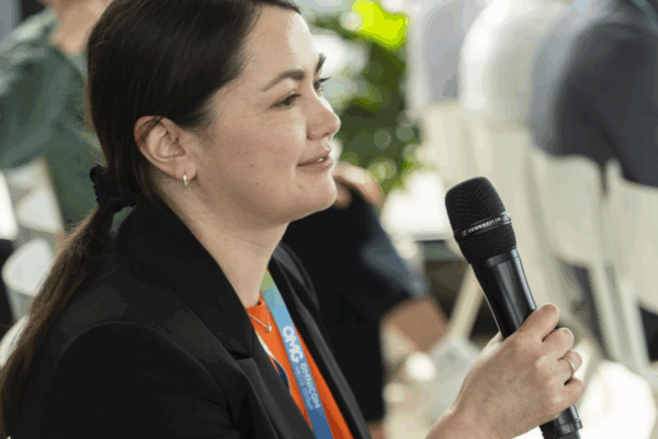 Frau mit Mikrofon während einer Präsentation – lebendige Arbeitsatmosphäre in der Agentur, Inspiration und Austausch im Vordergrund, Ideenkraft sichtbar.