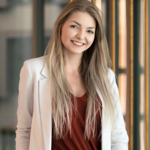 Mitarbeiterin mit langen blonden Haaren lächelt freundlich – Ausdruck von Vielfalt, Persönlichkeit und positiver Arbeitsatmosphäre.